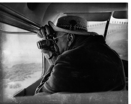 Black and white photo of Bill Garnett taking a photograph from his plane