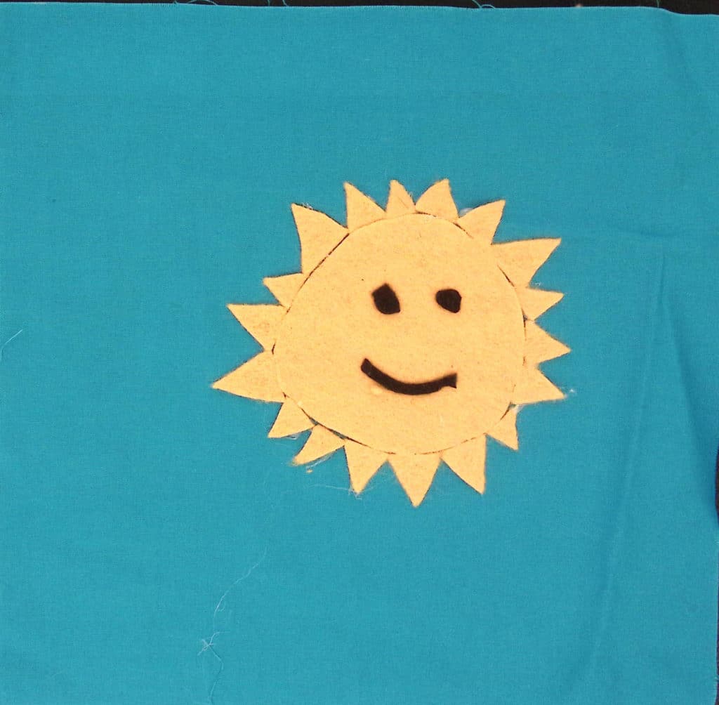 Blue square with a smiling yellow sun.