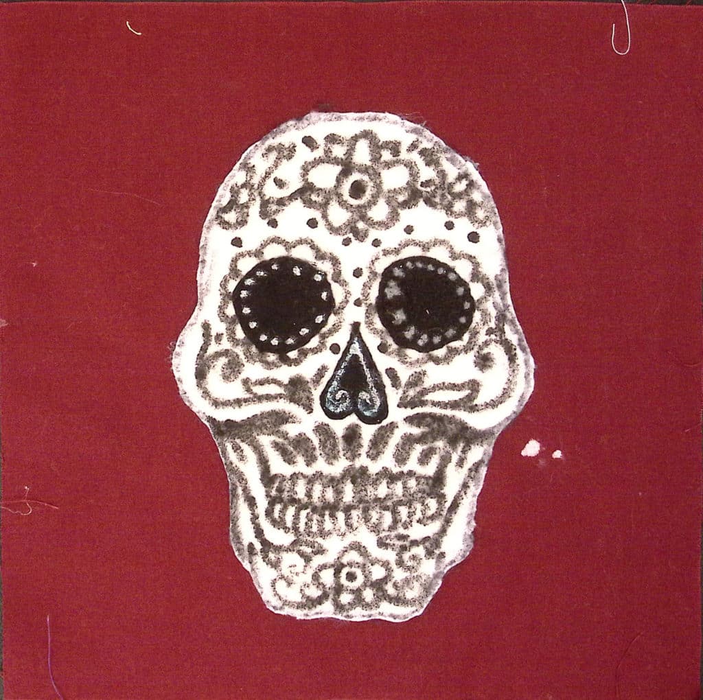 A burgundy square with an elaborate black and white calavera skull
