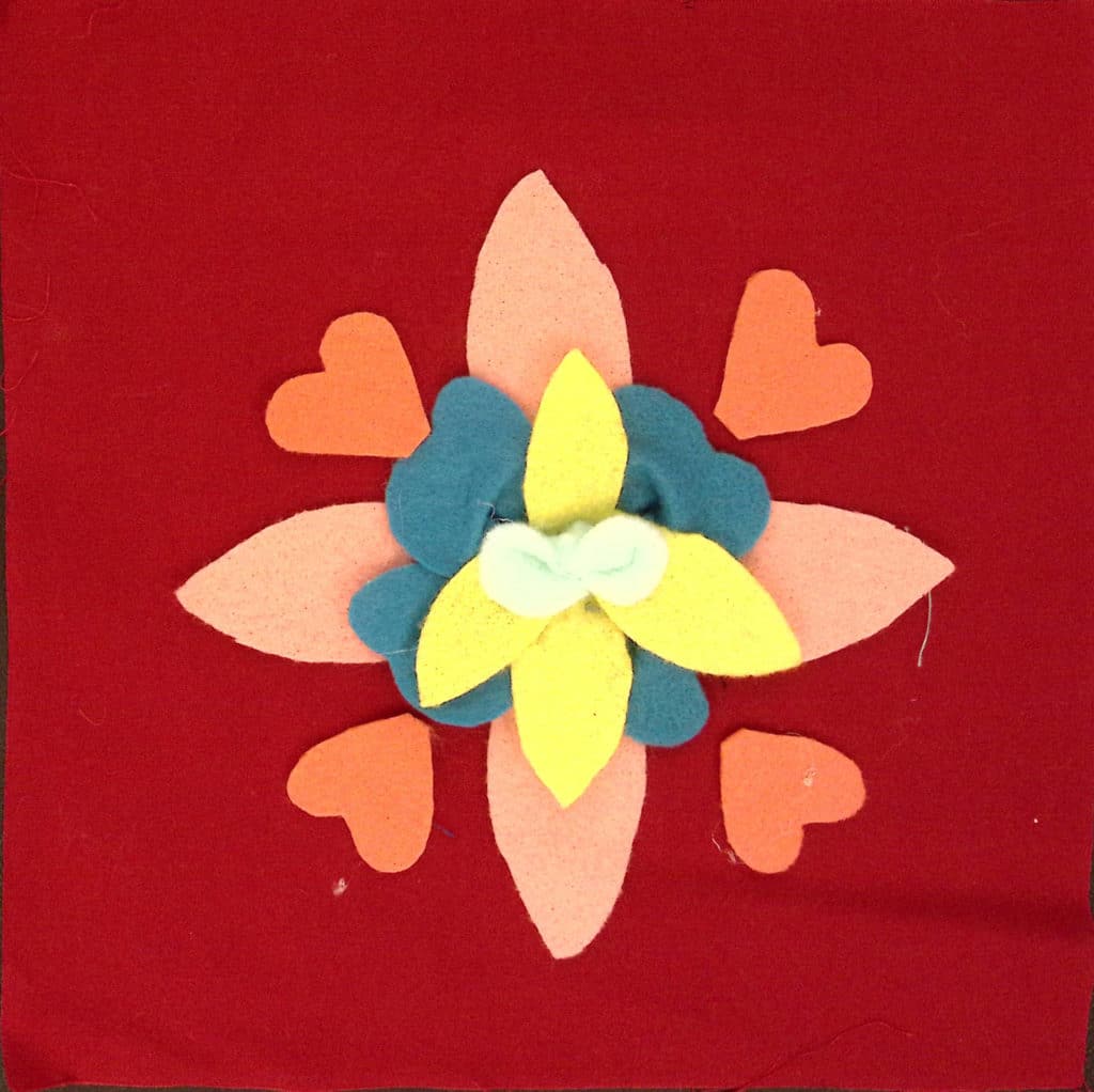A three-dimensional flower with yellow,blue and pink petals, with orange heart-shaped petals.