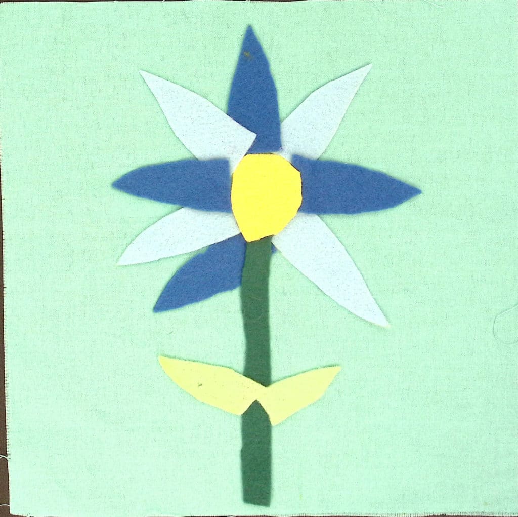 A light blue square with a flower with alternating dark and light blue petals.