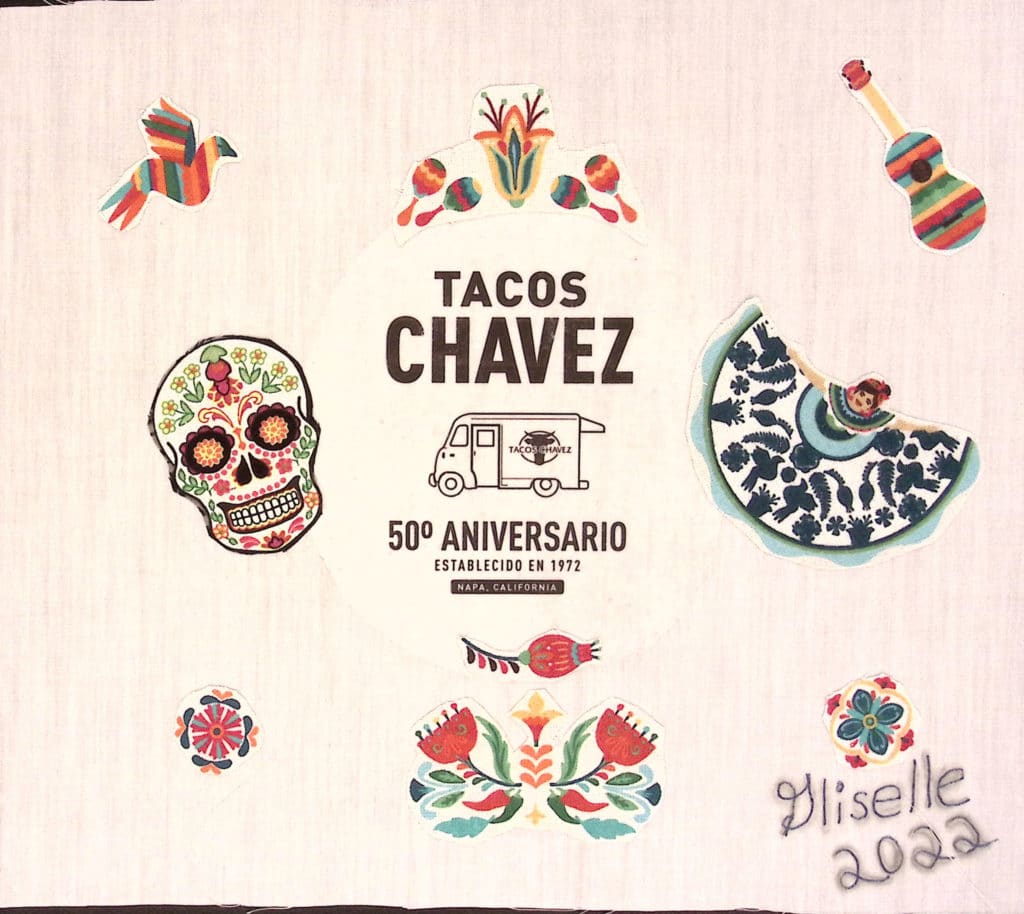 A white square with "Tacos Chavez 50th aniversario" with the food truck logo in the middle. Colorful skulls and dancers.