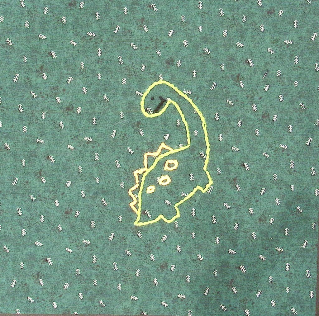 An embroidered long-necked dinosaur in green thread on a green background.