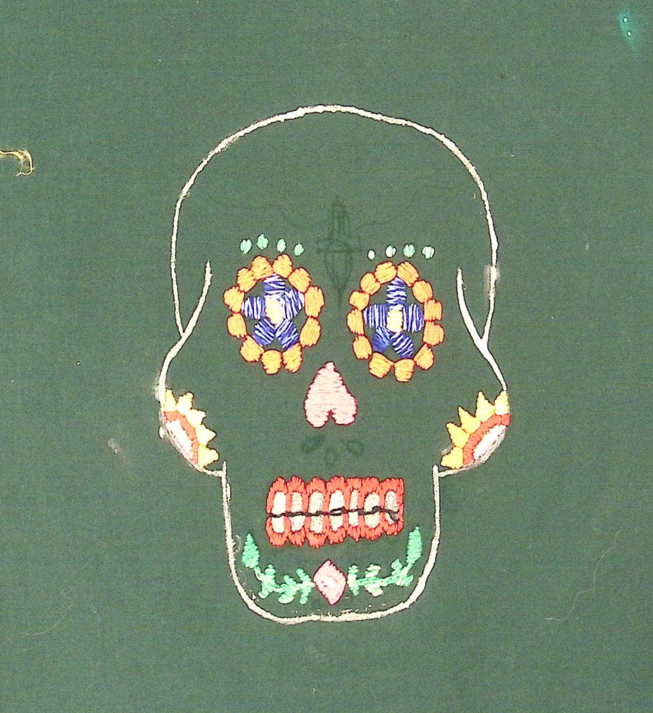 Embroidered calavera with multicolored thread on green background