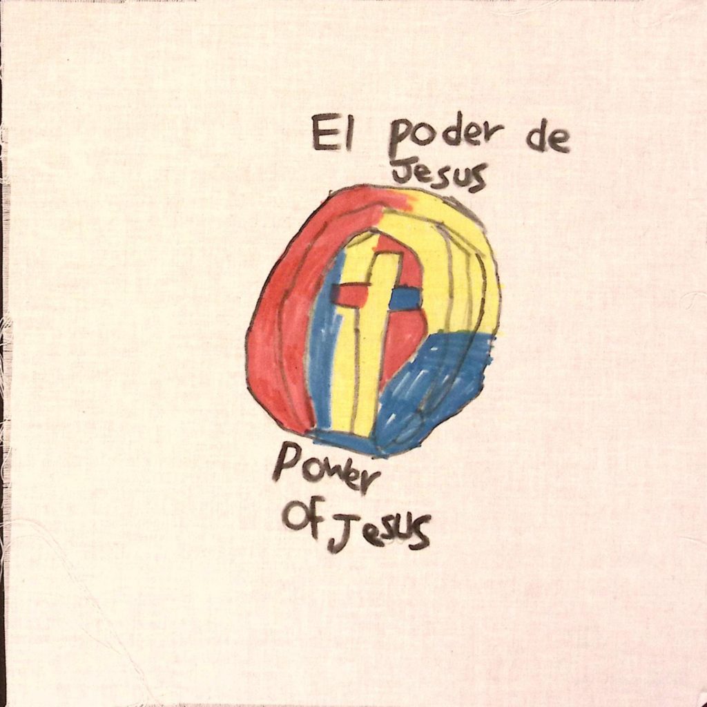A circle, filled in with red, yellow, and blue. and a cross in the center, colored yellow, with one blue arm, and one red. Text above reads, "El Poder de Jesus," and text on the bottom reads, "Power of Jesus."