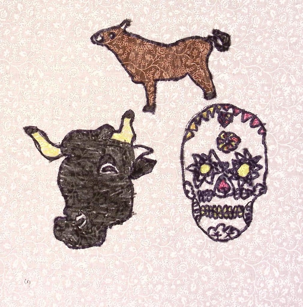 A brown donkey above the head of a black bull and a colorful skull covered in flowers.