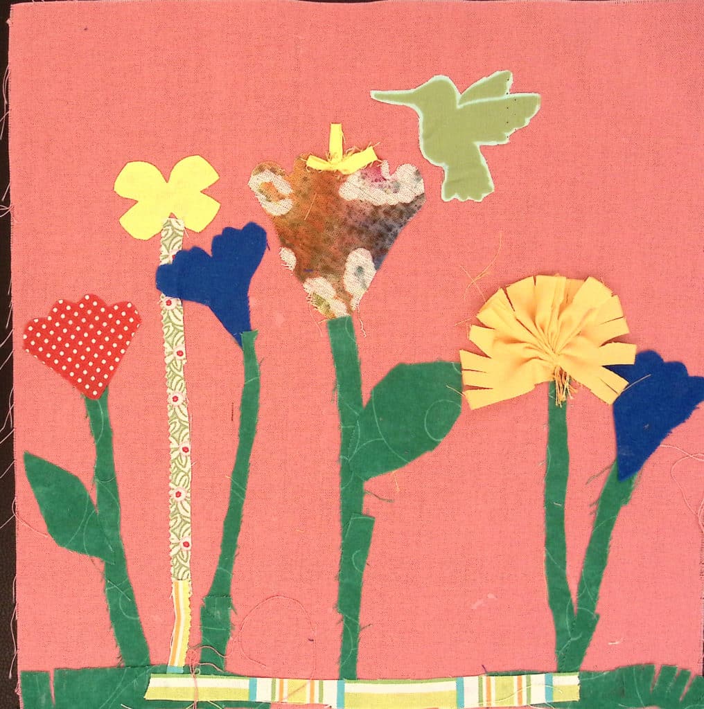 A pink square with multicolored flowers, marigolds and California poppies, with a green hummingbird.