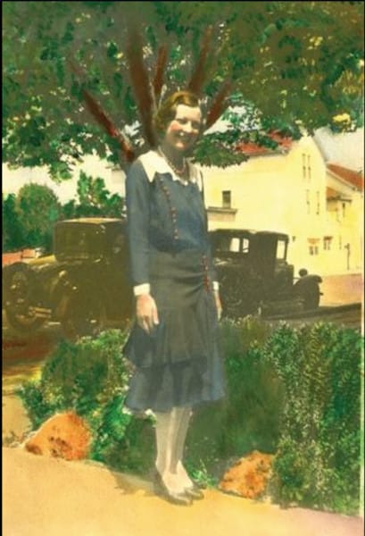 Colorized photograph of Dorothy Jaekle MacLean in a blue dress, standing in front of a hedge and a tree with a truck in the background.