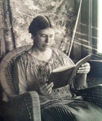 Helen Hoyt Lyman sitting in an armchair and reading a book.