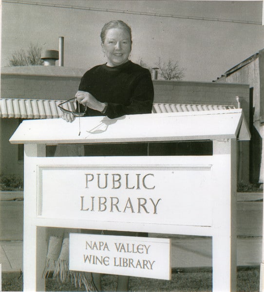 MFK Fisher standing behind the sign for the Napa Valley Wine Library.