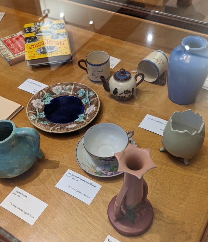 Cups, saucers, vases and other handmade ceramics in a display case.