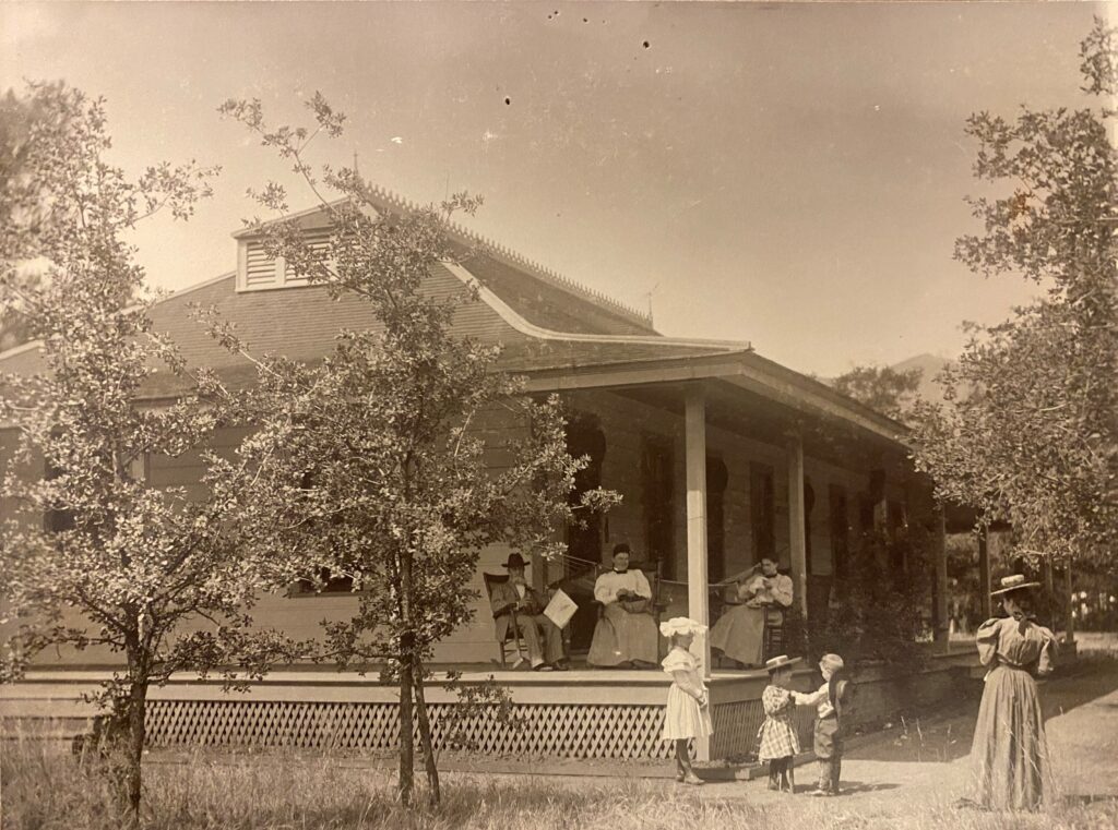 A family with three women, a man and three small children near the porch of a cabin at Aetna Springs resort.