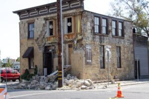 The image depicts a two-story stone building with extensive damage to its facade, caused by the 2014 South Napa Earthquake.